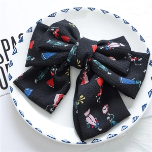 Detail view of large black chiffon bow hair clip with colorful cartoon character prints