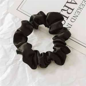 Détail d'un chouchou en satin noir avec texture de soie douce et plis de tissu élégants