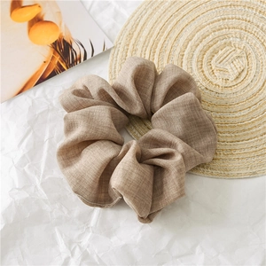 Detailed macro view of the natural linen texture and pleated folds on a beige scrunchie