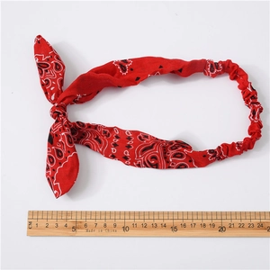 Red paisley print wire headband with rabbit ear bow on a white background with ruler