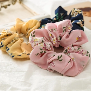 Detailed view of floral scrunchies set in yellow, pink and navy blue soft fabric