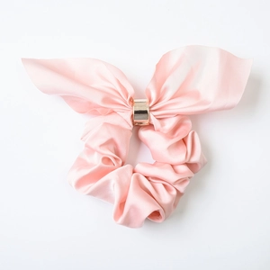Pink satin scrunchie with rabbit ear bow and golden metal ring for elegant hair styling