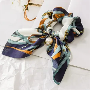 Detailed shot of elegant navy satin bow scrunchie with a white pearl pendant