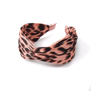 Pink leopard print knotted headband in smooth satin fabric with a stylish cross-twist design