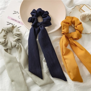 Detail of soft ribbed fabric scrunchies with long streamers in beige, navy and yellow