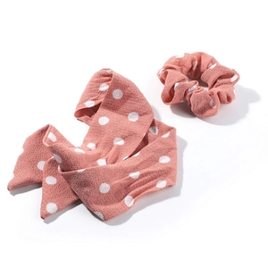 Close-up of pink polka dot scrunchie fabric texture and matching long hair ribbon detail
