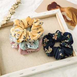 Floral print hair scrunchies in yellow green pink and navy blue displayed in a frame
