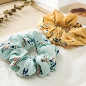 Detailed view of light blue and yellow floral chiffon scrunchies on a soft white background