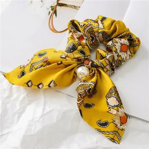 Detail of yellow floral satin scrunchie with a large elegant pearl pendant decoration