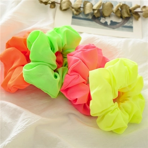 Dettaglio di un set di elastici neon in colori vivaci verde, rosa, arancione e giallo