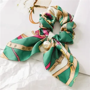 Detailed macro view of vintage green silk scrunchie with chain print and pearl pendant