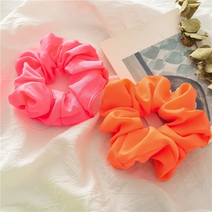 Dettaglio di elastici per capelli rosa e arancione neon con trama a pieghe morbide