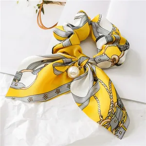 Detailed view of yellow floral silk scrunchie with long ribbons and pearl pendant charm