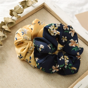 Detail of floral chiffon hair scrunchies on wooden frame with eucalyptus leaf