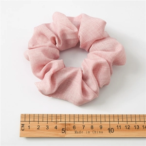 Pink pleated fabric hair scrunchie 10cm diameter shown with a wooden scale on white background