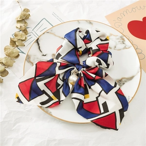 Détail d'un chouchou en tissu à motifs géométriques avec un pendentif perle blanche