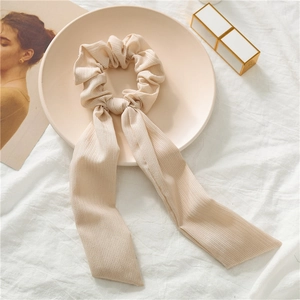 Detailed texture of beige vertical striped fabric on hair scrunchie with long ribbons