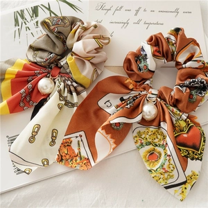 Detail of silk satin scrunchies with long rabbit ear ribbons and elegant pearl pendants