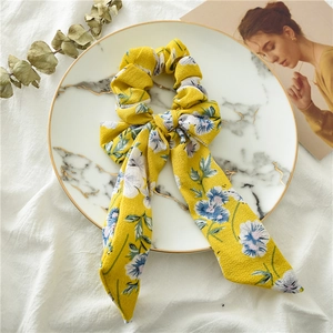 Detail of floral scrunchie with long ribbons on a white marble display tray