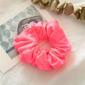 Dettaglio di un elastico per capelli rosa neon in morbido tessuto di chiffon plissettato