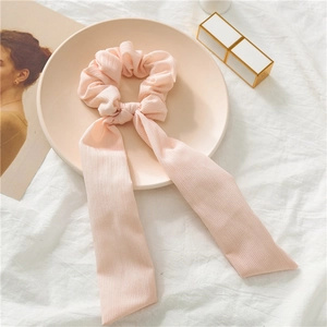 Detail showing pink chiffon scrunchie with vertical texture and long ribbons on a tray