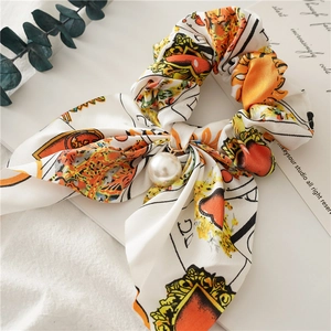 Close-up of printed satin scrunchie with rabbit ear ribbons and a large pearl charm