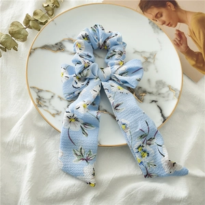 Detail of light blue floral scrunchie with long ribbon bow on marble plate