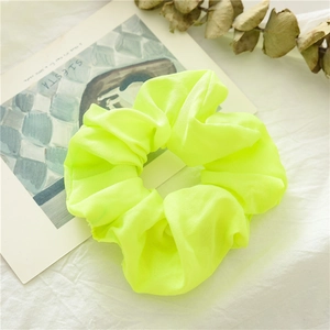 Vista dettagliata di un grande elastico scrunchie giallo fluo in chiffon con pieghe
