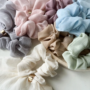 Detail of multi-color pleated hair scrunchies with metallic cylinder charms in soft pastel tones