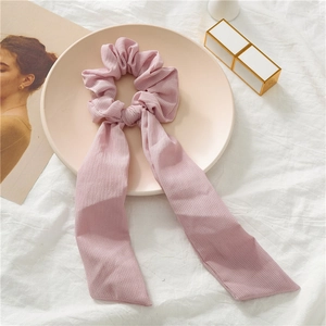 Detail of pink bow hair scrunchie with long ribbon streamers on a decorative tray