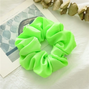 Dettaglio di un elastico per capelli verde neon con trama in chiffon su tessuto