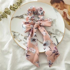 Close-up of pink floral chiffon bow hair tie with long streamers on marble tray
