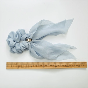 Detail of light blue ribbon scrunchie with gold metallic threads and a golden metal ring