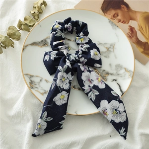 Detail of navy blue floral chiffon scrunchie with long streamers on marble plate