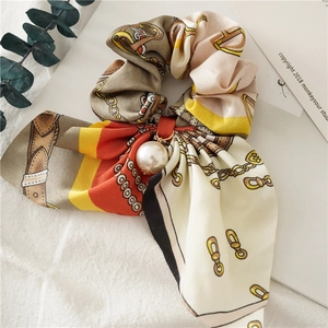 Detail showing elegant satin scrunchie with chain patterns and a large white pearl pendant