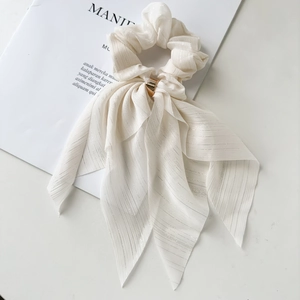 Detail of cream hair scrunchie with metallic silver stripes and golden metal buckle