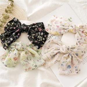 Detail view of four floral chiffon bow hair clips in black, white, green, and pink colors