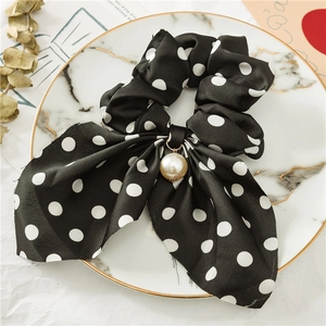 Chouchou en satin à pois avec une grande perle sur un plateau en marbre élégant