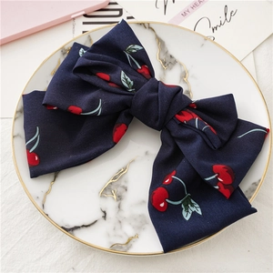 Détail du nœud papillon en mousseline bleu marine avec motif d'imprimé cerise rouge