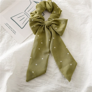 Détail d'un chouchou en mousseline verte à pois blancs avec un long ruban élégant