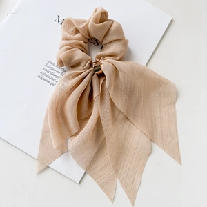 Close-up of champagne bow scrunchie with metallic threads and gold buckle detail
