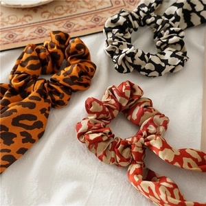 Close-up of leopard and cow print satin scrunchies with streamers on white fabric