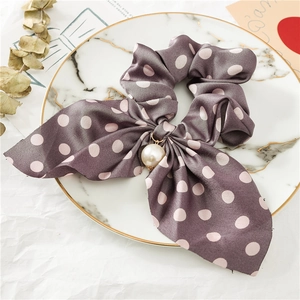 Vue détaillée du chouchou en satin violet à pois roses avec breloque en perle élégante