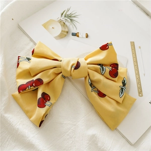 Détail de la grande barrette à cheveux en mousseline jaune avec motif de cerises rouges