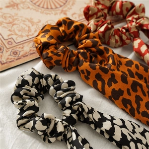 Detailed view of satin leopard print hair scrunchies with long streamers in three colors