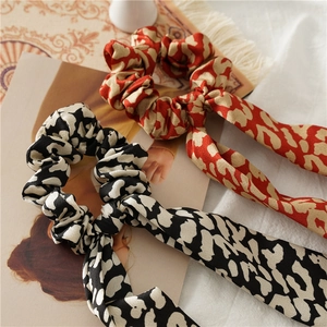Elegant satin leopard print scrunchies with long ribbons on a vintage magazine base