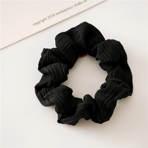 Nahaufnahme eines schwarzen Haargummis mit Rippenstruktur und weichem Cord-Stoff-Design
