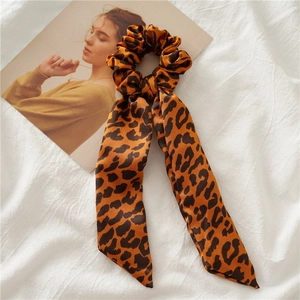 Detail shot of leopard print satin hair scrunchie with long ribbons on white fabric