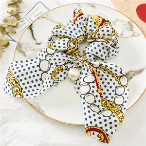 Vue détaillée du chouchou en satin avec ruban de soie, pendentif perle et motif chaîne