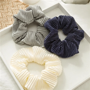 Three pleated satin hair scrunchies in grey, navy, and cream white colors for women